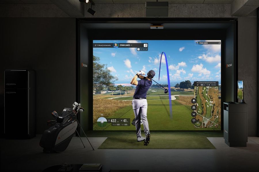 Full view of an indoor golf simulator setup with golfer, clubs, and modern room decor