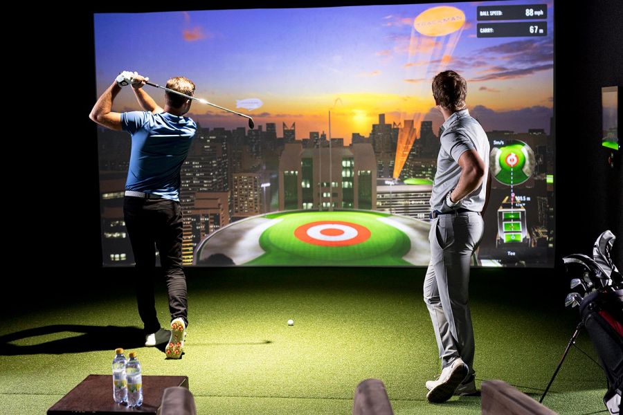 Two men playing a target game on a large indoor golf simulator screen